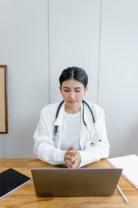 doctor sits at desk in front of computer